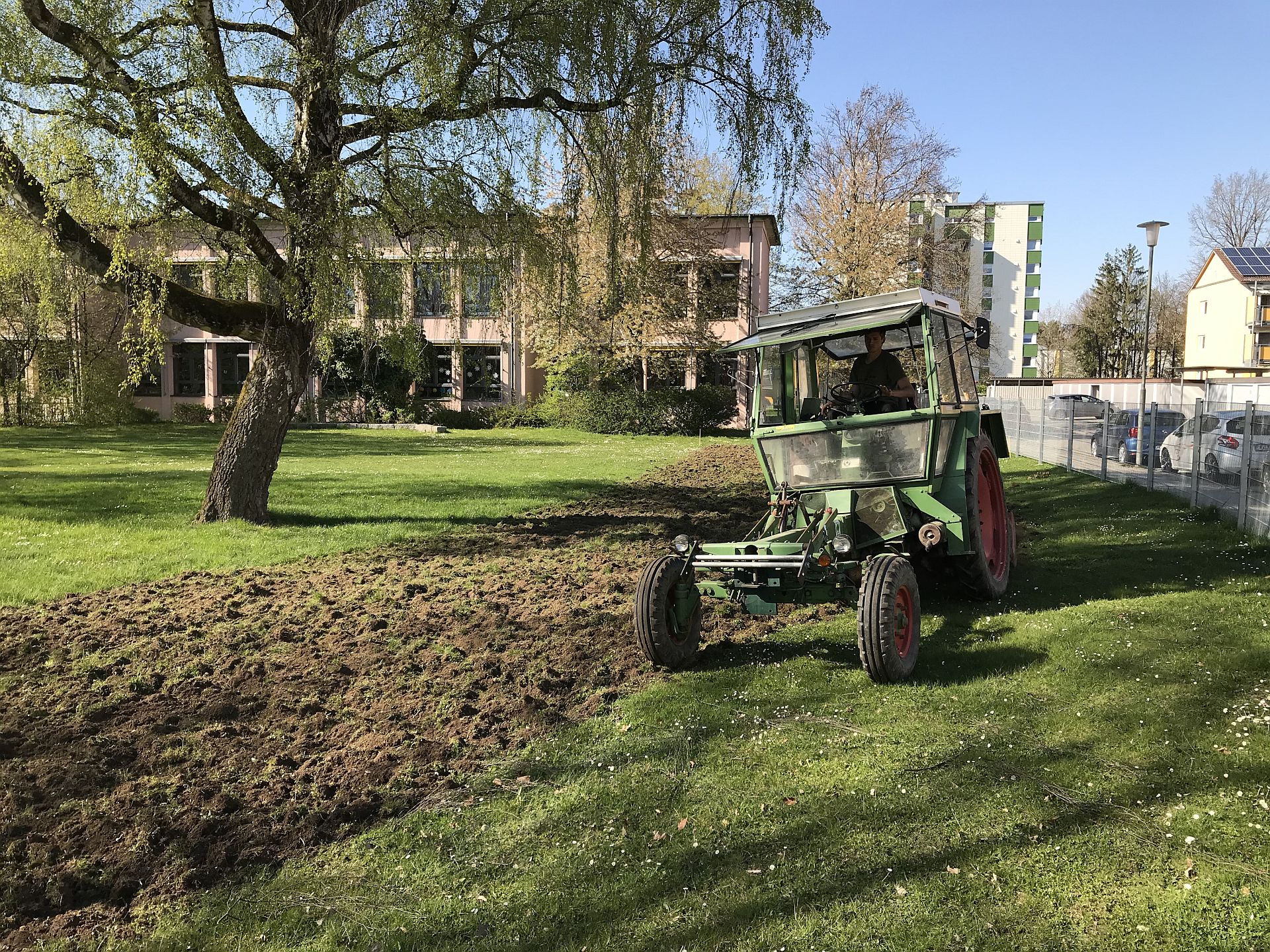 Ein Traktor bereitet die Wiese für die Pflanzen des Naturlernraums vor Ein Traktor bereitet die Wiese für die Pflanzen des Naturlernraums vor